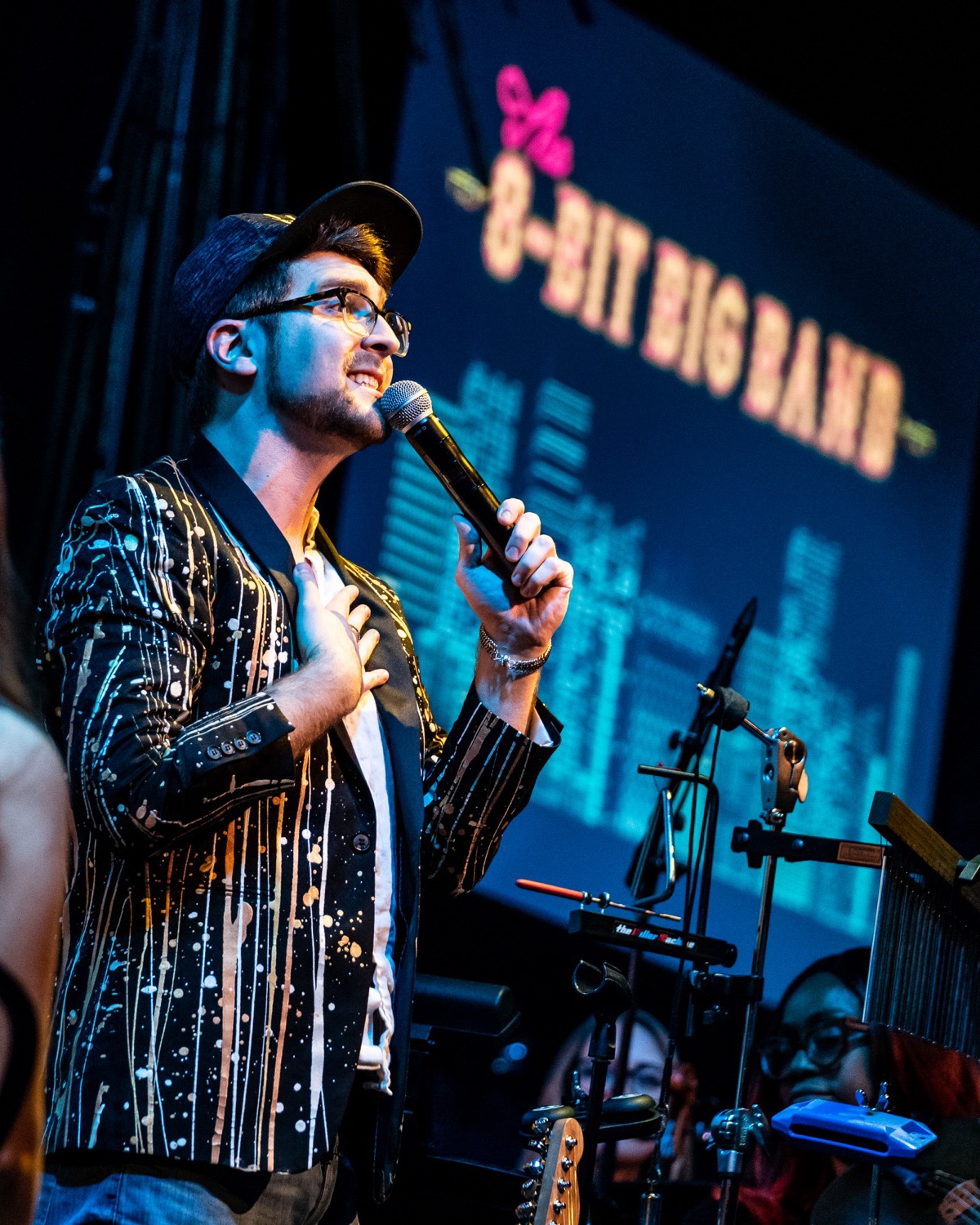 A singer fronts the 8-Bit Big Band in front of the band’s video-game screen